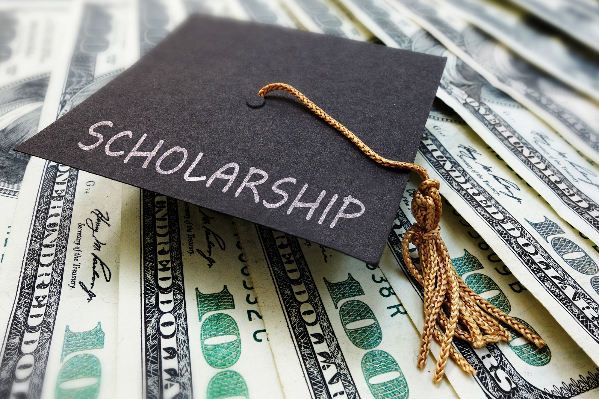 Graduation cap that says scholarship on top of money